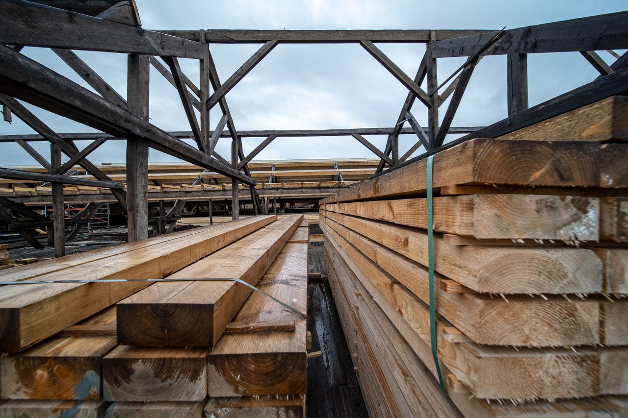 portfolio-01 Stacked timber planks in an outdoor industrial storage area under a cloudy sky.